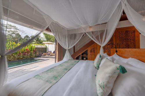 a bedroom with a bed with a canopy and a pool at Keliki Luxury Lodge in Ubud