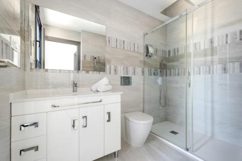 a white bathroom with a shower and a toilet at Apartament Sea Senses Summer in Punta Prima