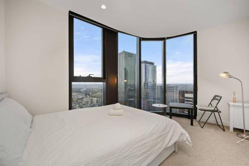 een slaapkamer met een wit bed en grote ramen bij Level 59 Delightful City Central 3B2B1C Apartment in Melbourne