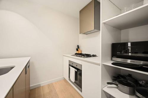 een witte keuken met een fornuis en een magnetron bij Level 59 Delightful City Central 3B2B1C Apartment in Melbourne