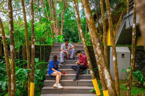 eine Gruppe von Menschen, die auf der Treppe eines Hauses sitzen in der Unterkunft The Hosteller Wayanad in Vythiri