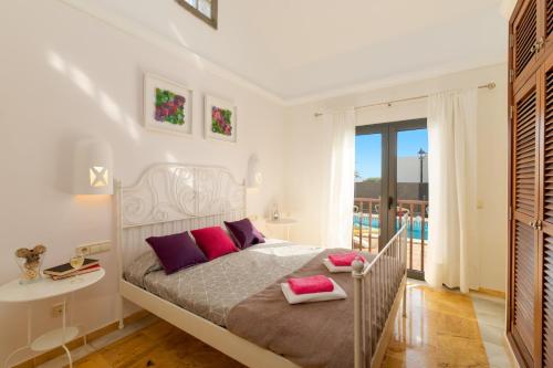ein weißes Schlafzimmer mit einem Bett und einem Balkon in der Unterkunft Villa Alhambra by Villa Plus in Playa Blanca