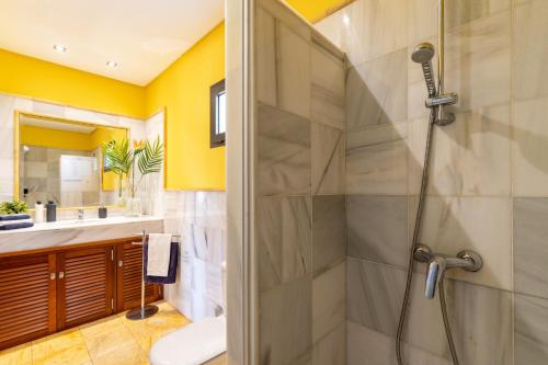ein Bad mit einer Dusche mit gelben Wänden in der Unterkunft Villa Alhambra by Villa Plus in Playa Blanca