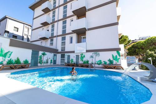 a woman in a swimming pool in front of a building at Hotel Palma de Majorca in Bibione