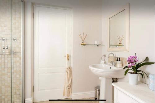 a white bathroom with a sink and a mirror at Guest suite - Leafy Constantia Guest House in Cape Town