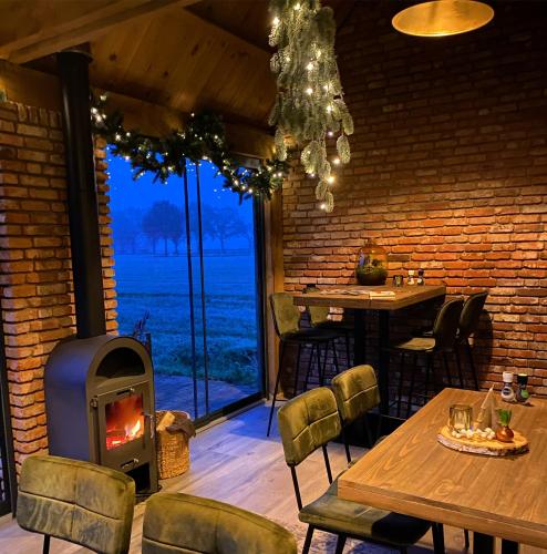 a fireplace in a restaurant with tables and chairs at Domestico Bed & Breakfast in Lage Mierde