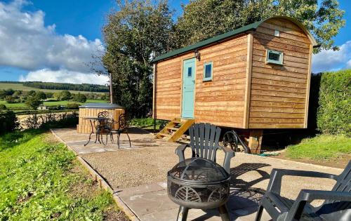 een houten tiny house op een patio met een grill bij Herefordshire Escape, Hot Tub, Firepit, Views, BBQ in Leominster