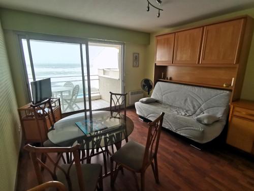 - un salon avec un lit et une table ainsi qu'une salle à manger dans l'établissement Le Petit Bargeouri - Face mer avec piscine, à Les Sables-dʼOlonne