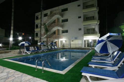 a hotel with a swimming pool with chairs and umbrellas at New York Plaza Hotel Apartments in Paphos City