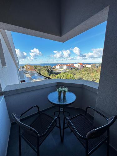a table and two chairs in a balcony with a view at Aparthotel Plat in Kožino