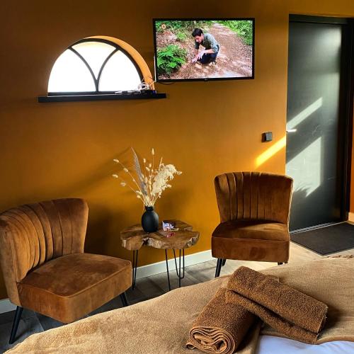 a bedroom with two chairs and a tv on the wall at Domestico Bed & Breakfast in Lage Mierde