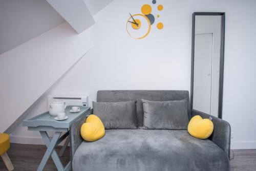 a living room with a gray couch with yellow pillows at ★Le Petit Cosy Vincennes★ in Vincennes