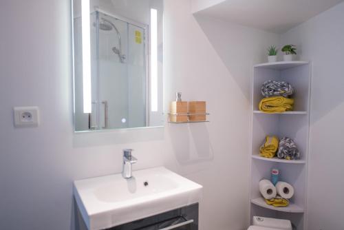 a white bathroom with a sink and a mirror at ★Le Petit Cosy Vincennes★ in Vincennes