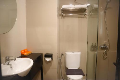 La salle de bains est pourvue de toilettes, d'un lavabo et d'une douche. dans l'établissement Front One Hotel Gombong, à Gombong
