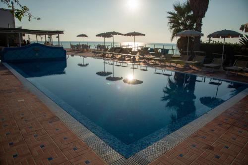 a swimming pool with chairs and umbrellas and the ocean at Hotel Albatros in Ischia