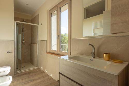ein Badezimmer mit Waschbecken und Toilette und einem Fenster in der Unterkunft Villa Poggio al Sole by VacaVilla in Foiano della Chiana