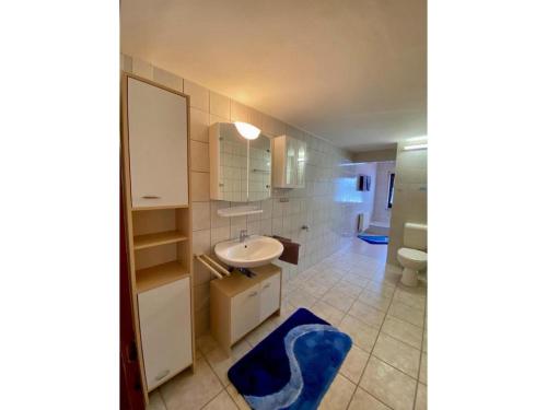 ein Badezimmer mit einem weißen Waschbecken und einem blauen Teppich in der Unterkunft Cafe-Restaurant Vedder in Herscheid