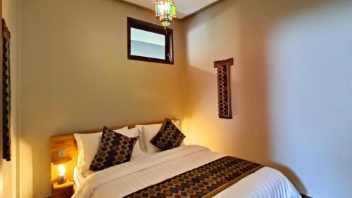 a bedroom with a bed with pillows and a window at Dalai Tropical in Kuta Lombok