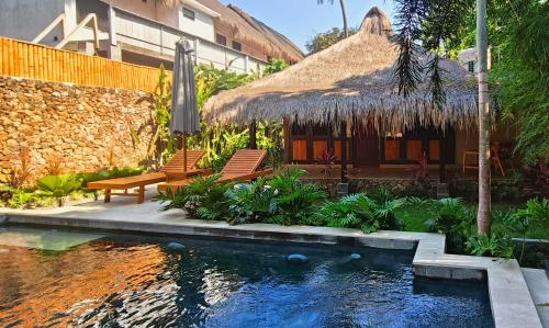a resort with a swimming pool and a thatched building at Dalai Tropical in Kuta Lombok
