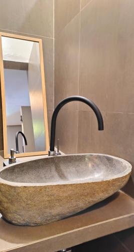 a stone sink in a bathroom with a mirror at Dalai Tropical in Kuta Lombok
