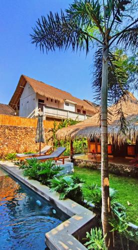 a resort with a swimming pool and a palm tree at Dalai Tropical in Kuta Lombok