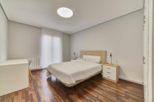 a white bedroom with a bed and a wooden floor at Apartamento El Rincón Logroñes by Clabao in Logroño