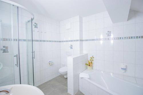 a white bathroom with a toilet and a shower at Ferien Hotel Spree-Neisse in Neuhausen