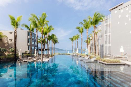 a swimming pool with palm trees and buildings at Oceanfront Beach Resort in Patong Beach