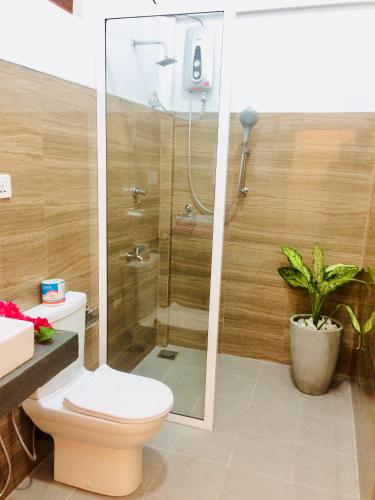 a bathroom with a shower with a toilet and a plant at Tropicana Home Stay in Arugam Bay