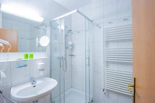 a white bathroom with a shower and a sink at Ferien Hotel Spree-Neisse in Neuhausen