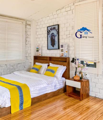 a bedroom with a bed with yellow and white pillows at Giăng's House Farmstay & Glamping in Bao Loc