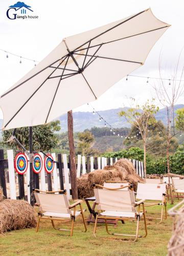 a group of lawn chairs and an umbrella at Giăng's House Farmstay & Glamping in Bao Loc