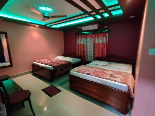 two beds in a room with green lights at DAS HOTEL in Darjeeling