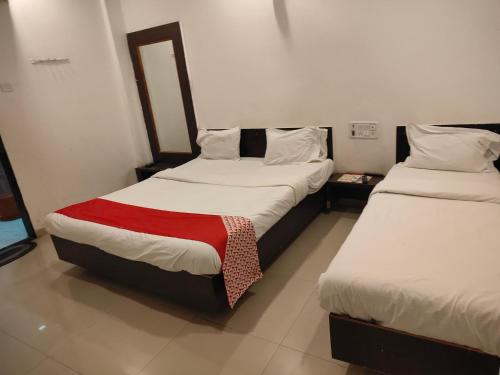 two beds in a hotel room with a red blanket at S Sai Inn in Shirdi
