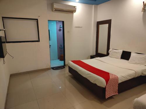 a bedroom with a large bed with a red blanket at S Sai Inn in Shirdi