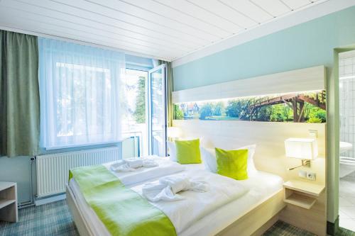 1 dormitorio con 1 cama blanca grande con almohadas amarillas en Ferien Hotel Spree-Neisse, en Neuhausen