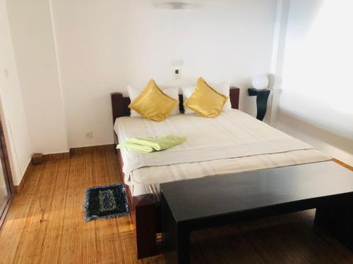 a bedroom with a bed with yellow pillows on it at Hikka Beach Flat in Hikkaduwa