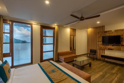 a bedroom with a bed and a large window at Meghavan Resort By DLS Hotels in Dharamshala