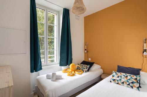 deux lits dans une chambre avec des rideaux verts dans l'établissement Le Poulpe - Proche plage de Rochebonne, à Saint-Malo