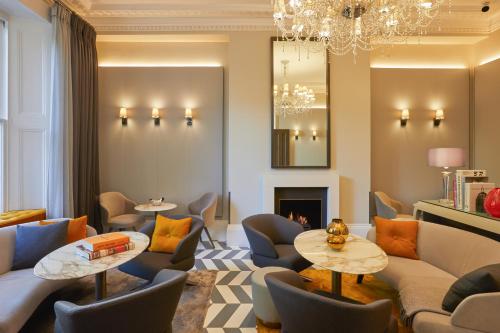 a living room with couches and tables and a chandelier at Eccleston Square Hotel in London
