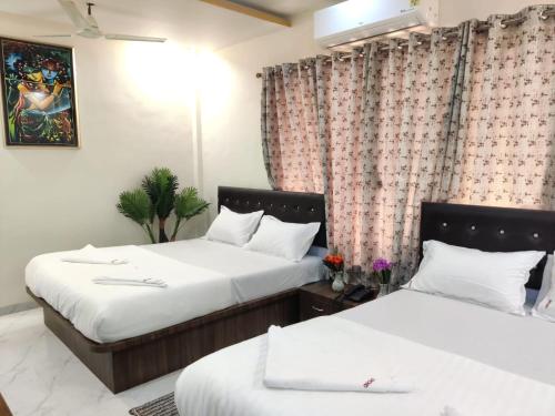 two beds in a hotel room with curtains at Hotel Orchid House Navi Mumbai in Navi Mumbai