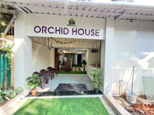 an entrance to an orchid house with chairs and grass at Hotel Orchid House Navi Mumbai in Navi Mumbai