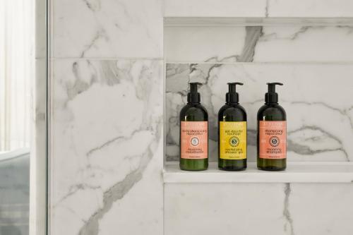 three bottles of wine sitting on a shelf in a bathroom at Eccleston Square Hotel in London