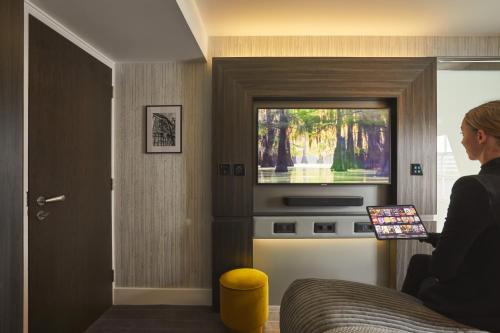 a woman sitting in a bed watching a television at Eccleston Square Hotel in London