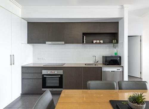 a kitchen with a table and chairs and a stove at WhitsunStays - The Regal (2br/2bth, Central) in Mackay