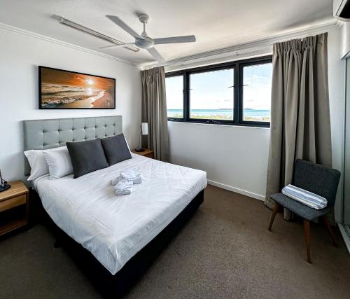 Un dormitorio con una cama y una silla y ventanas. en WhitsunStays - The Regal (2br/2bth, Central), en Mackay