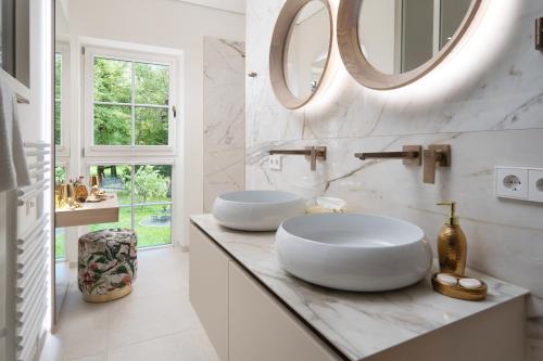 a white bathroom with two sinks and a mirror at SCHLOSSRESIDENZ - Boutique Apartments & Hotel Suiten in Schloß Ricklingen