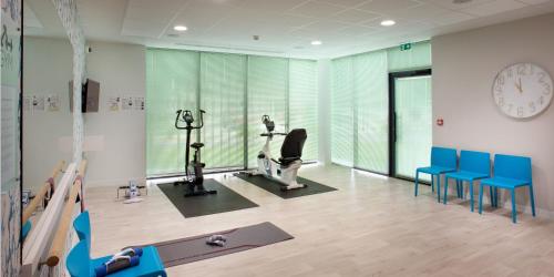 un gimnasio con equipo de ejercicios, sillas azules y reloj en Résidence Services Seniors DOMITYS - Villa Ulma en Lille