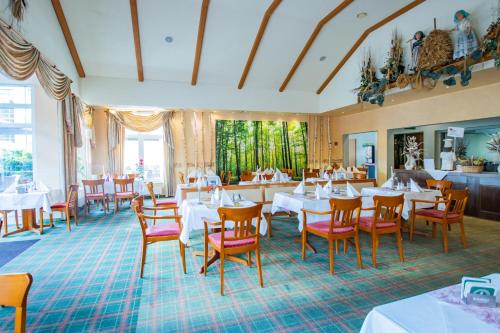 a restaurant with white tables and red chairs at Ferien Hotel Spree-Neisse in Neuhausen