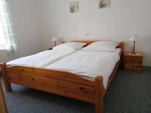 a bedroom with a wooden bed with white sheets and pillows at Weingut-Ferienwohnung Heinz Dostert in Nittel